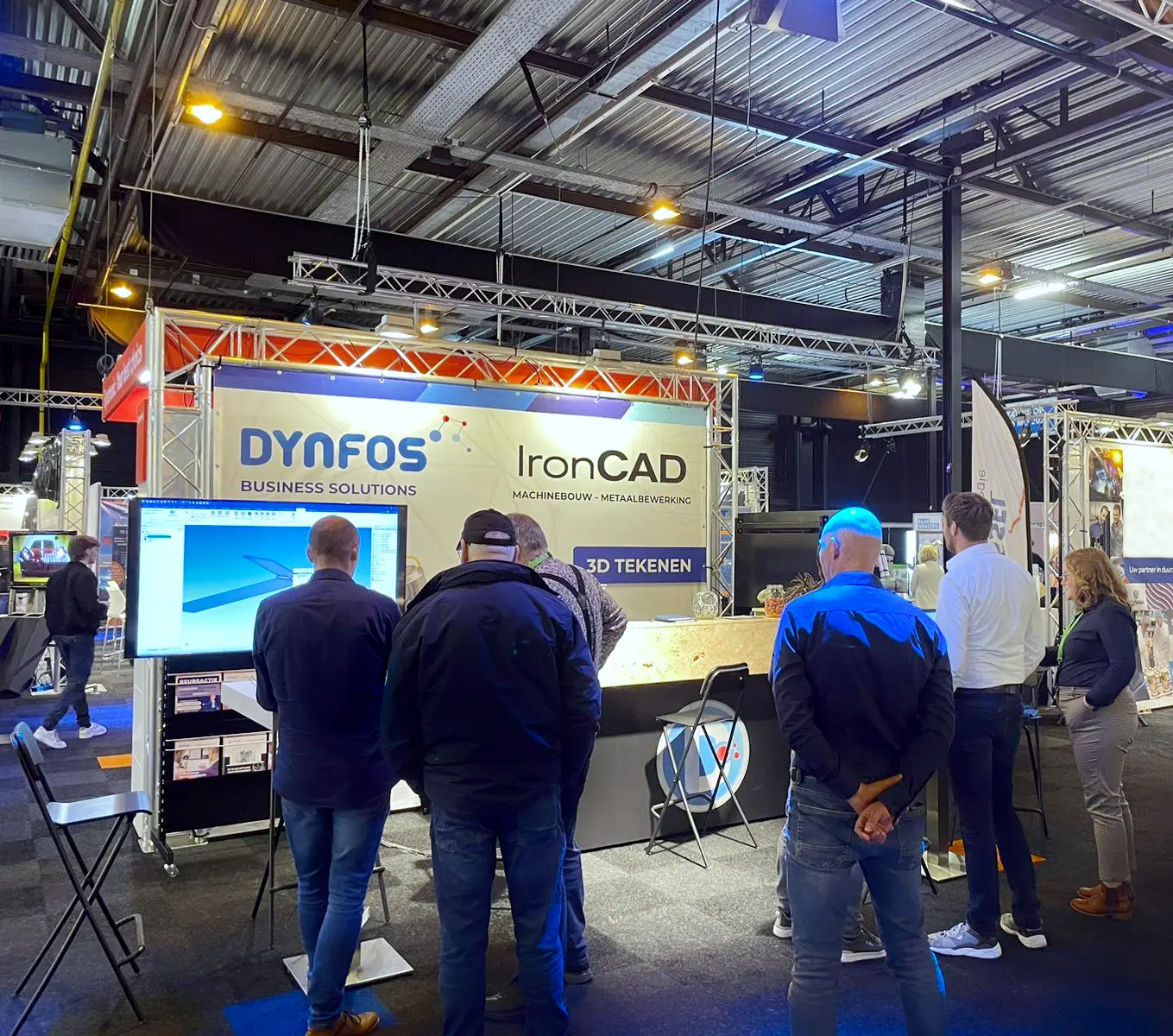 Beursstand van IronCAD met demonstratie van 3D-tekenen op groot scherm, bezoekers kijken mee.