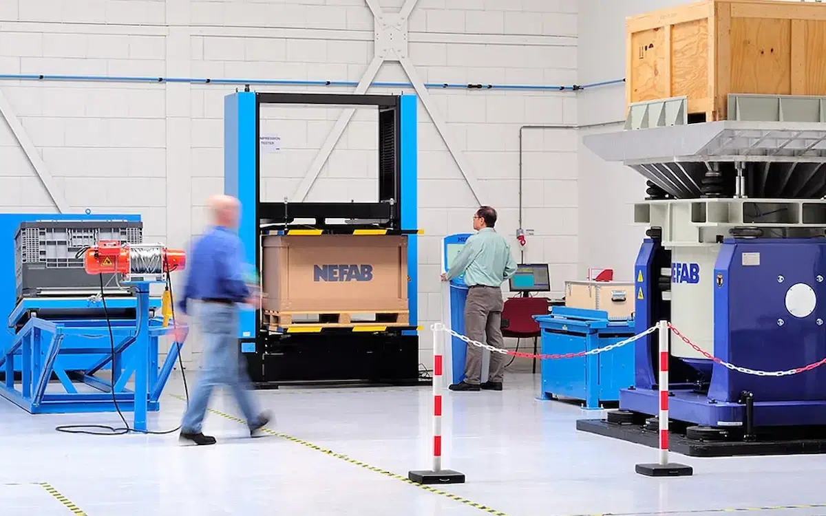 Machine for making packaging material at Nefab's plant, with workers at work.