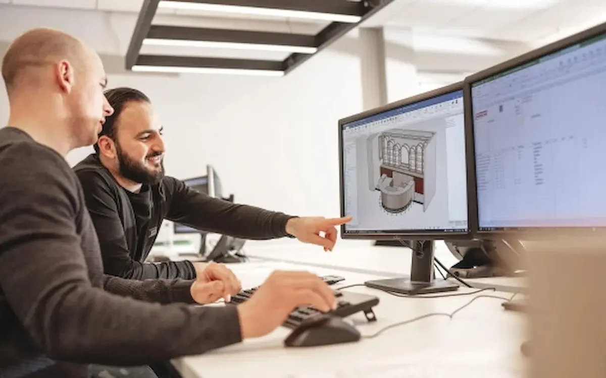 Work planners at Harmeling point to an IronCAD design on their computer screen.