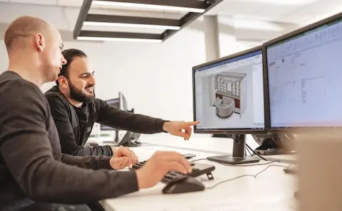 Werkvoorbereiders van Harmeling wijzen naar een IronCAD-ontwerp op hun computerscherm.