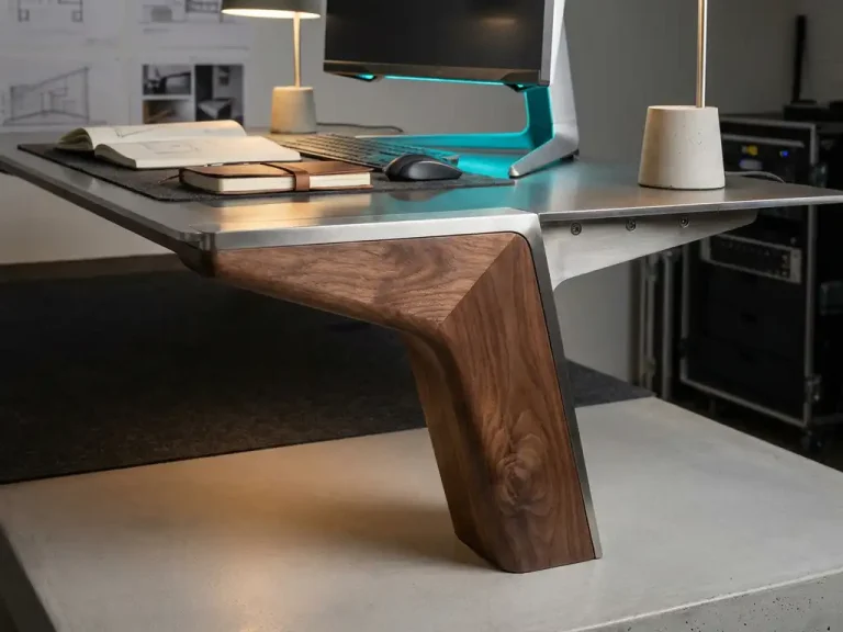 Houten tafelpoot verbonden met geborsteld stalen beugel op modern designersbureau naast computerworkstation