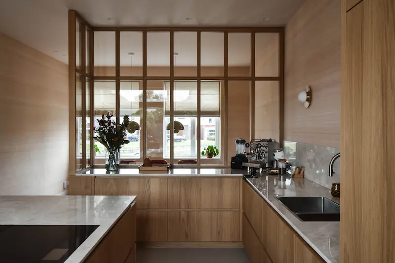 Detailfoto van maatwerkkeuken met houten lades, marmeren achterwand en hoogwaardige afwerking