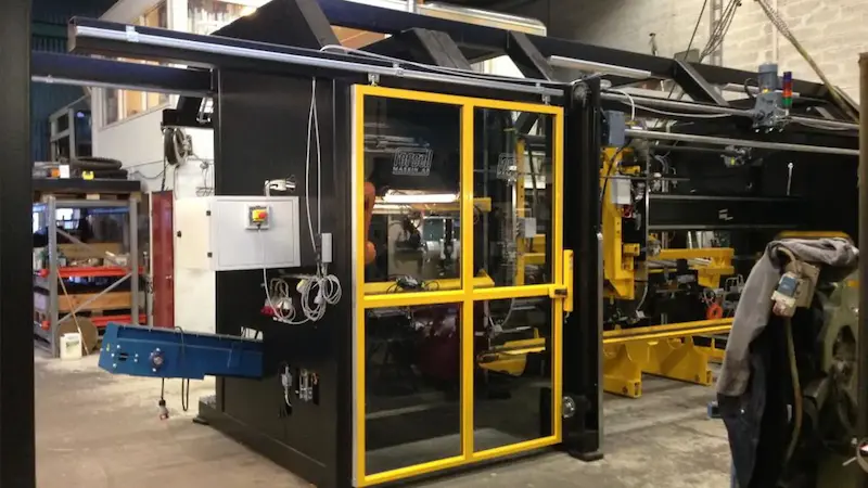 Klantspecifieke productiemachine van Forsell Maskin met zwarte behuizing en gele veiligheidsdeuren.